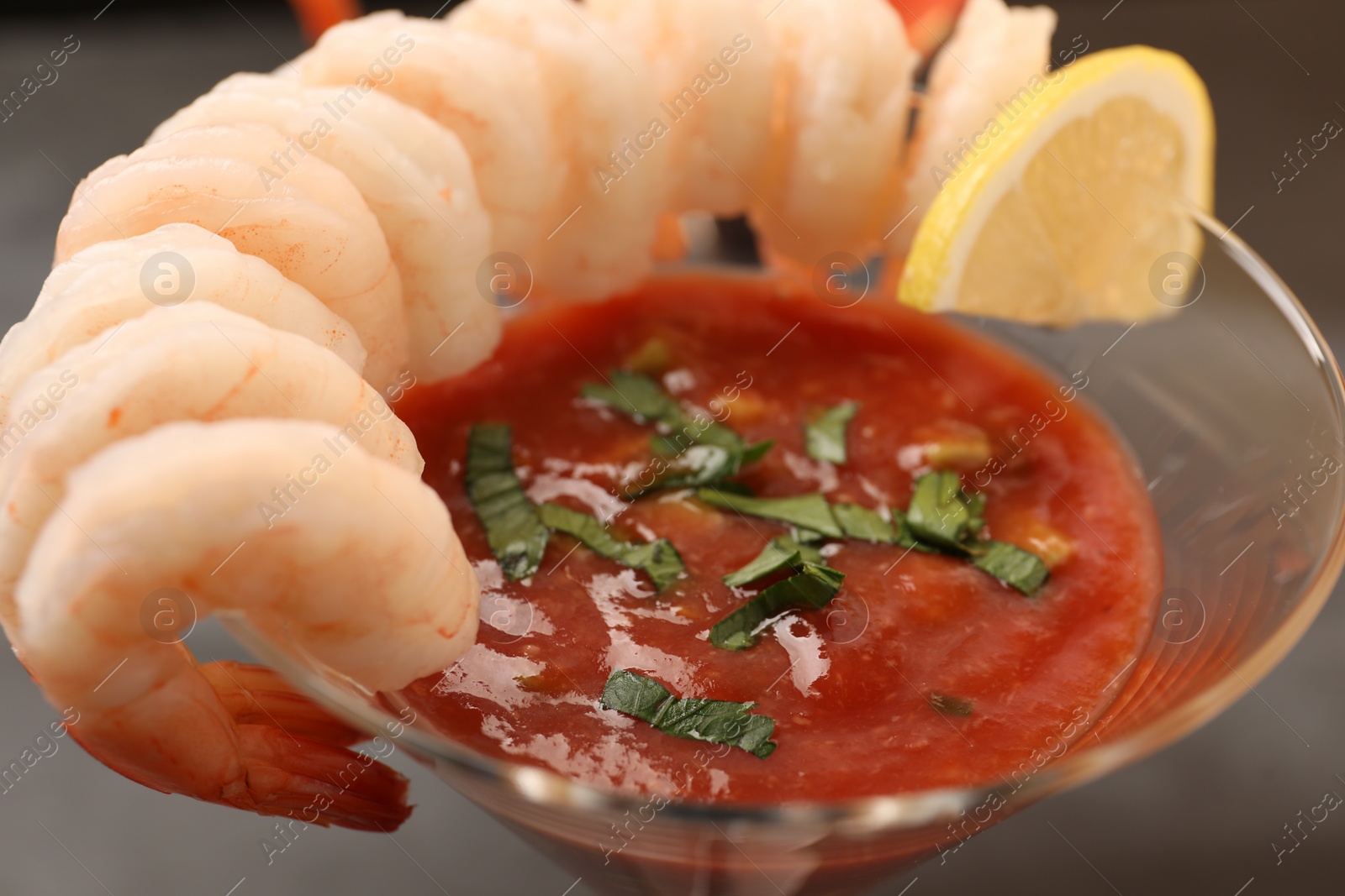 Photo of Tasty shrimp cocktail with sauce in glass and lemon on table, closeup