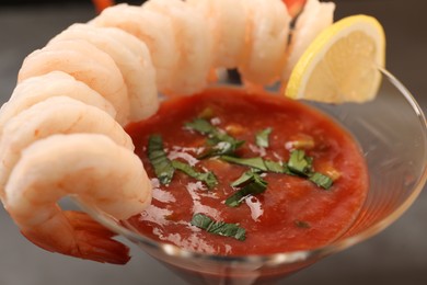 Photo of Tasty shrimp cocktail with sauce in glass and lemon on table, closeup