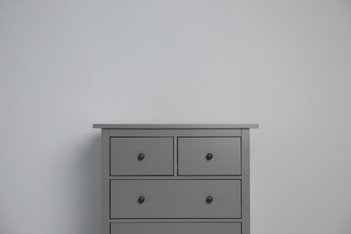 Photo of Grey chest of drawers on light background. Space for text