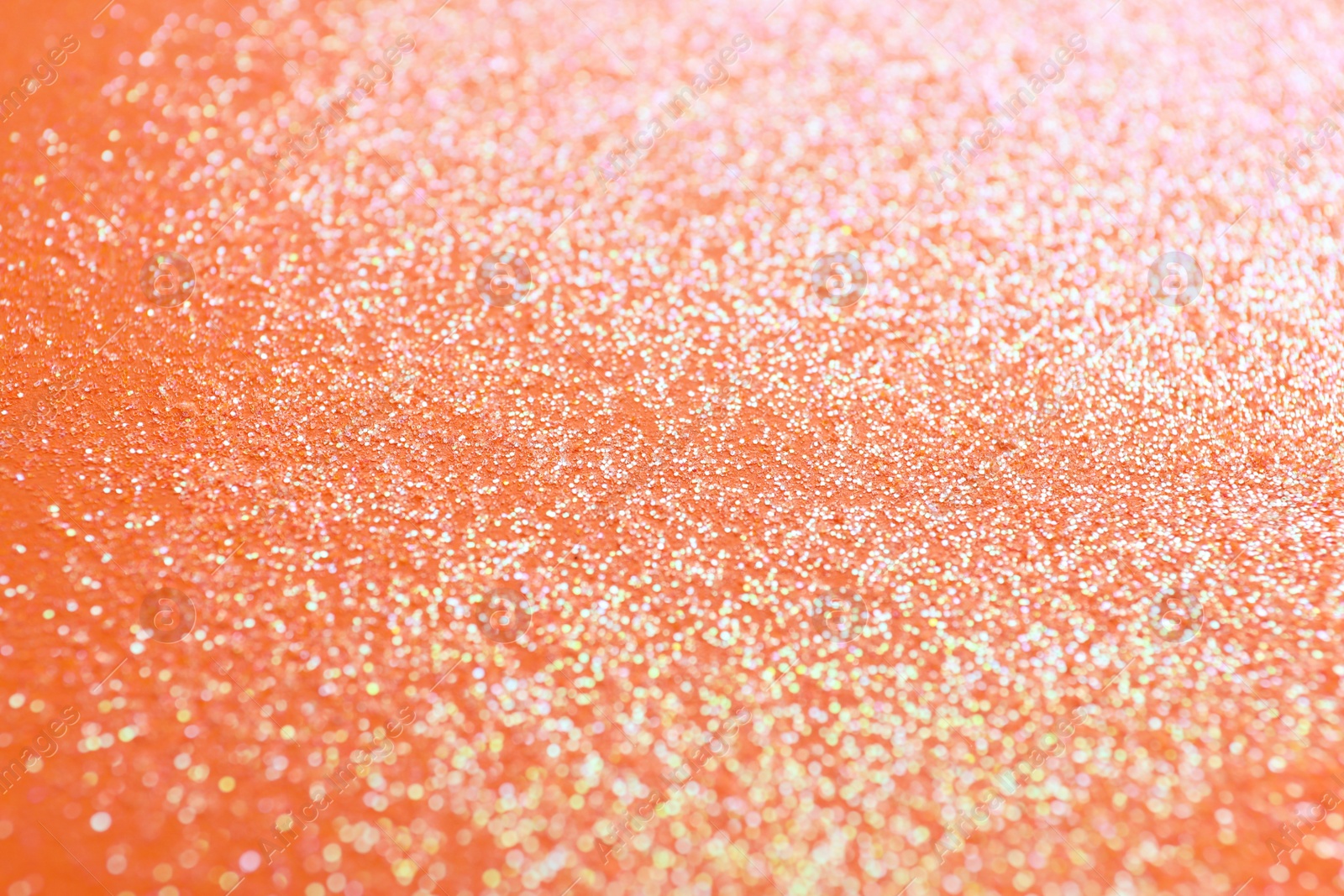 Photo of Shiny bright glitter on orange background, closeup