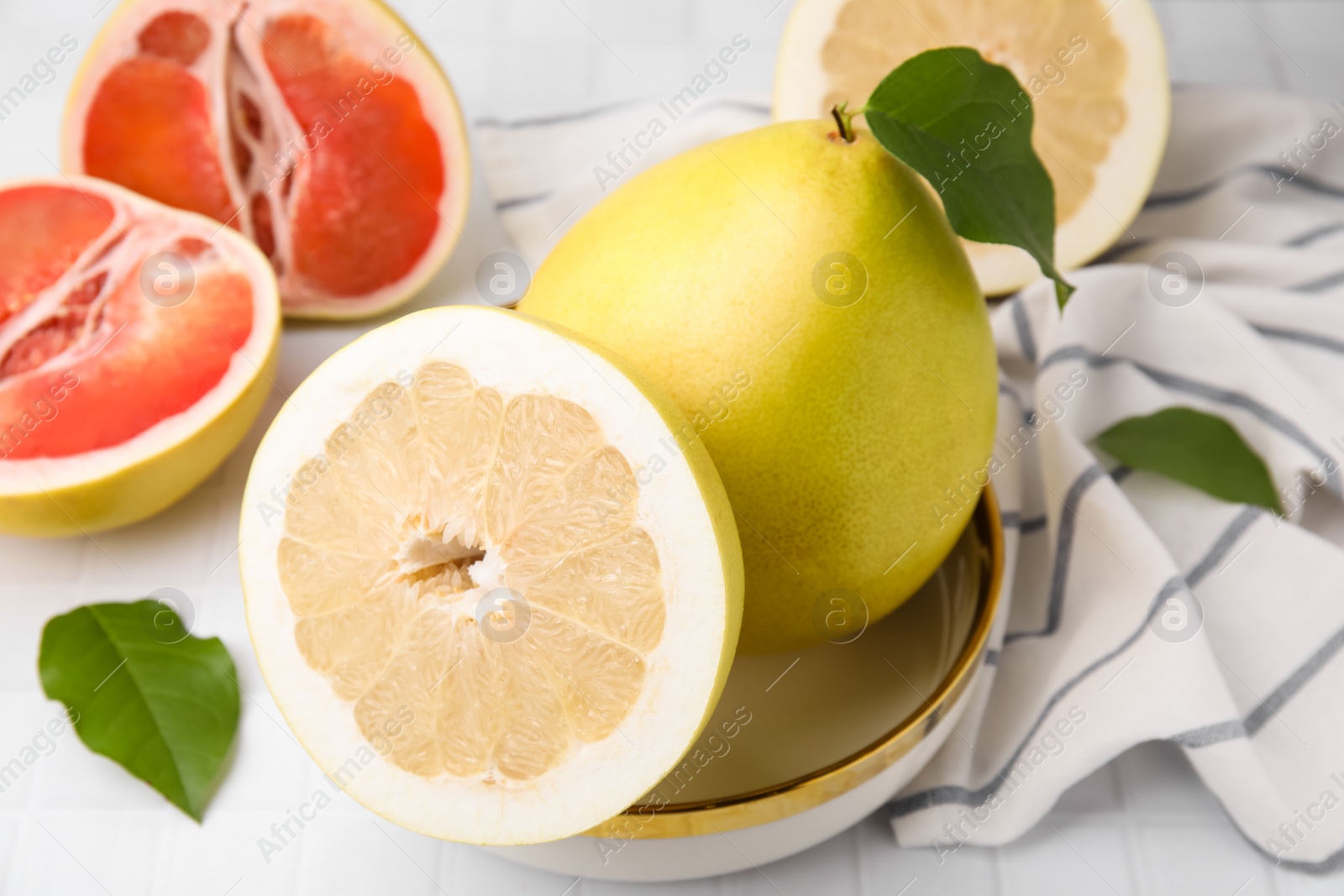 Photo of Tasty pomelo fruits on white tiled table, closeup