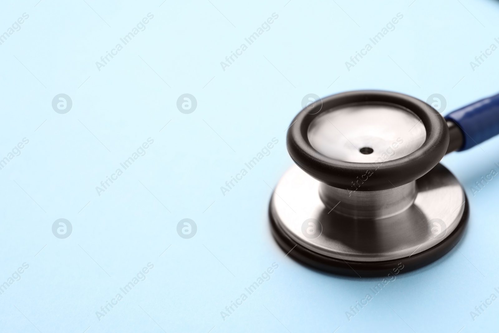 Photo of Stethoscope on light blue background, closeup. Space for text