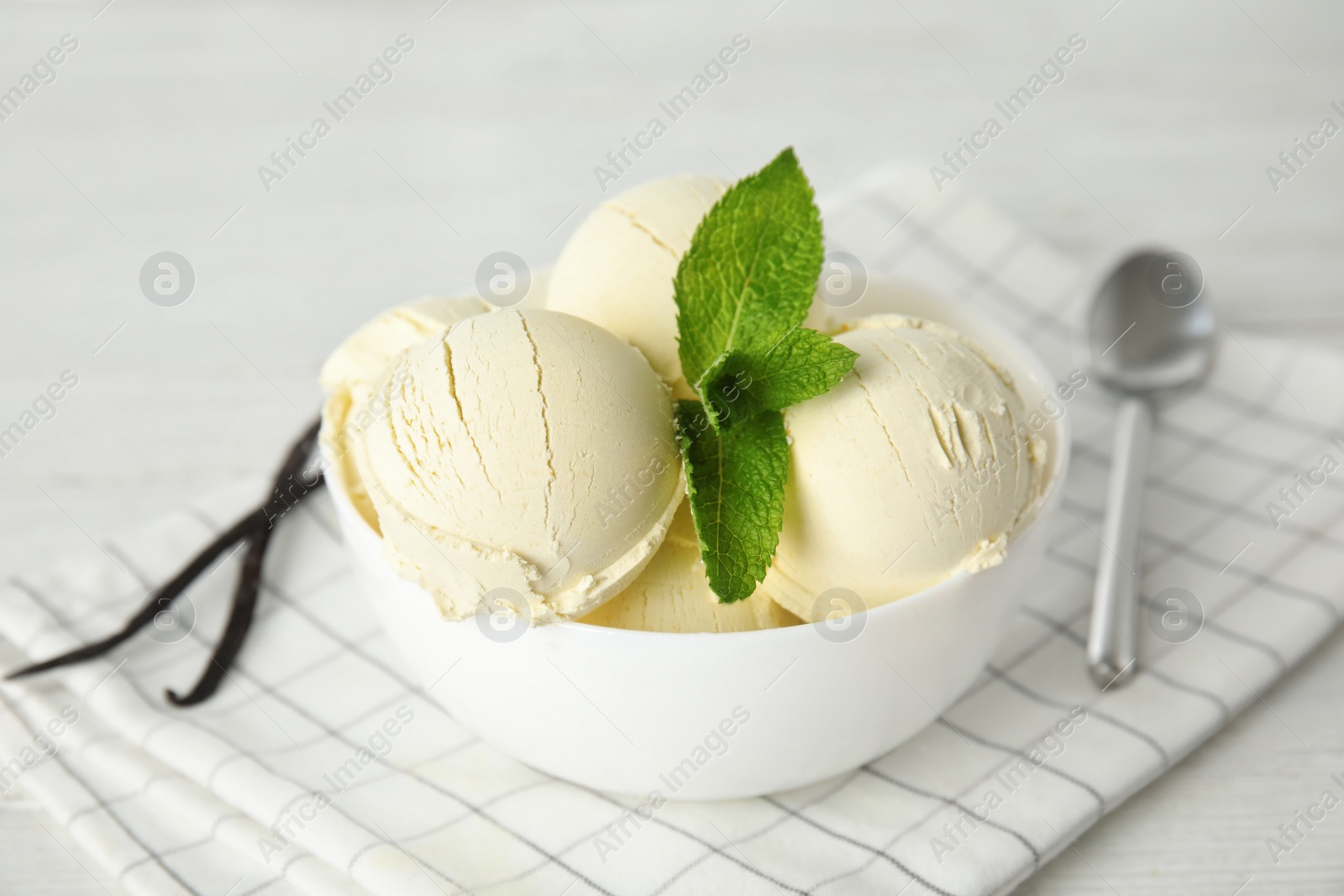 Photo of Delicious vanilla ice cream with mint in bowl served on table