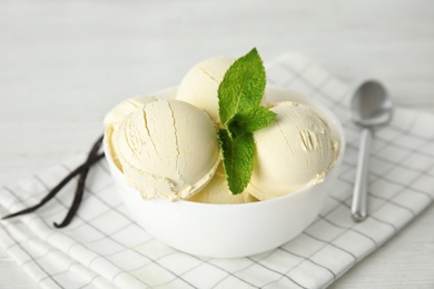 Delicious vanilla ice cream with mint in bowl served on table
