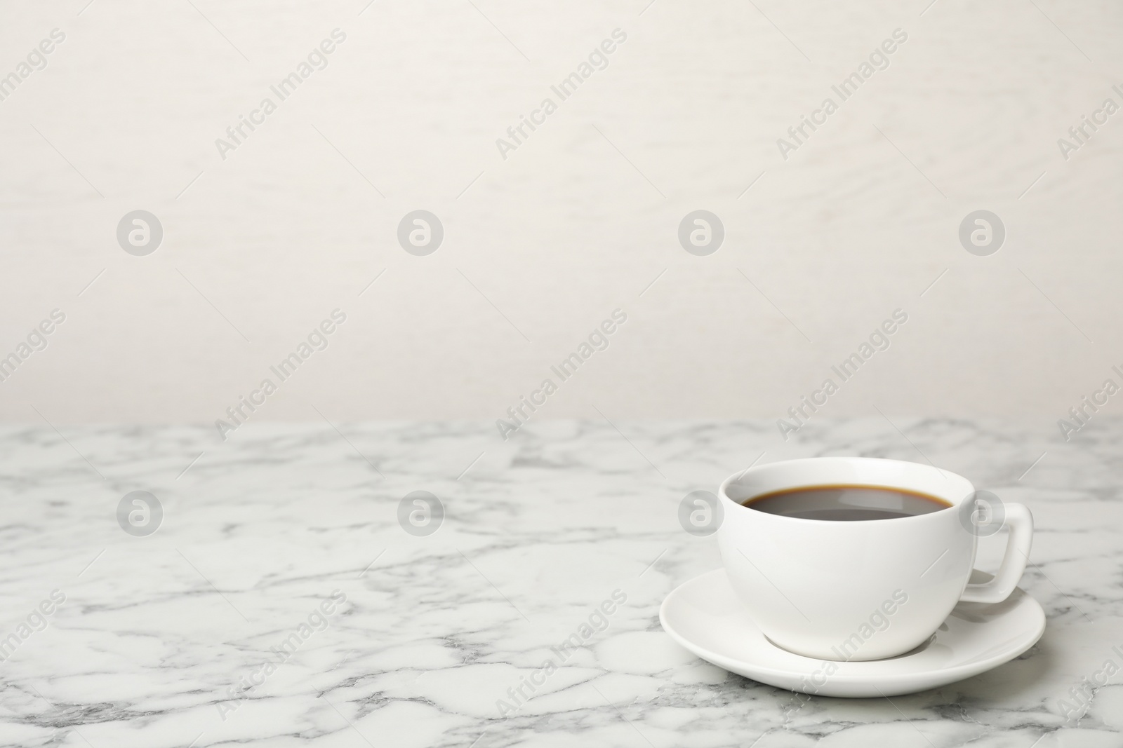 Photo of White ceramic cup with hot aromatic coffee on table