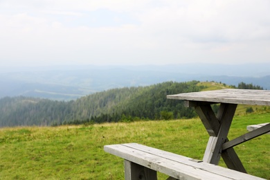 Photo of Picturesque landscape with wooden picnic table and mountain forest on background