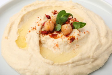 Photo of Plate of tasty hummus with garnish, closeup