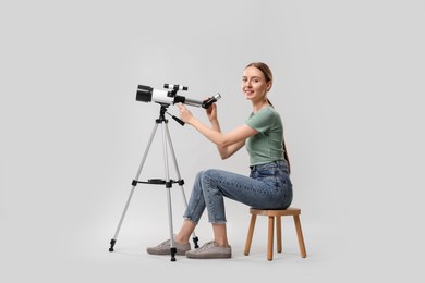 Photo of Young astronomer with telescope on grey background