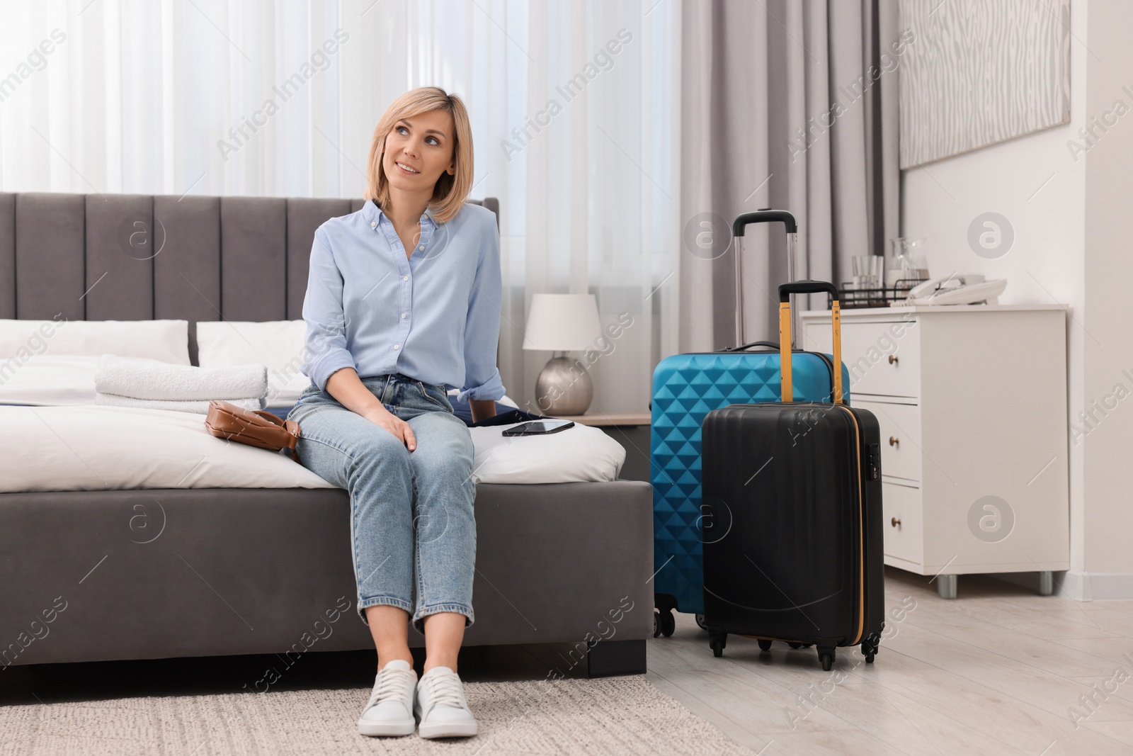 Photo of Smiling guest relaxing on bed in stylish hotel room