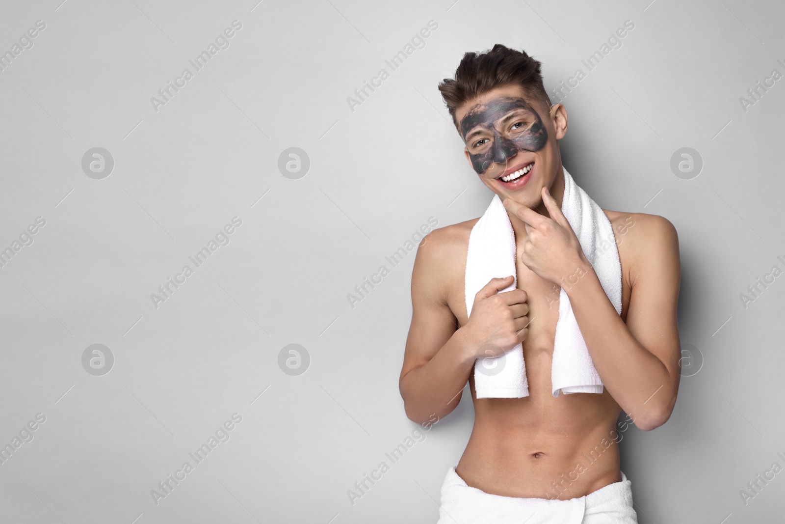 Photo of Handsome man with clay mask on his face against light grey background. Space for text