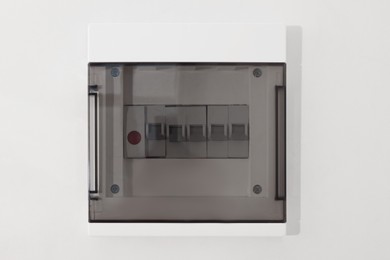 Photo of Closed fuse box on beige wall, closeup