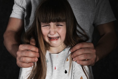 Crying little girl and adult man on dark background, closeup. Child in danger