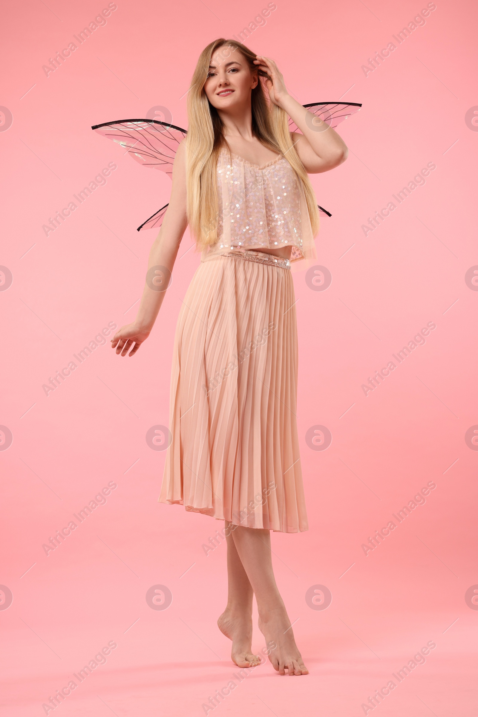 Photo of Beautiful girl in fairy costume with wings on pink background