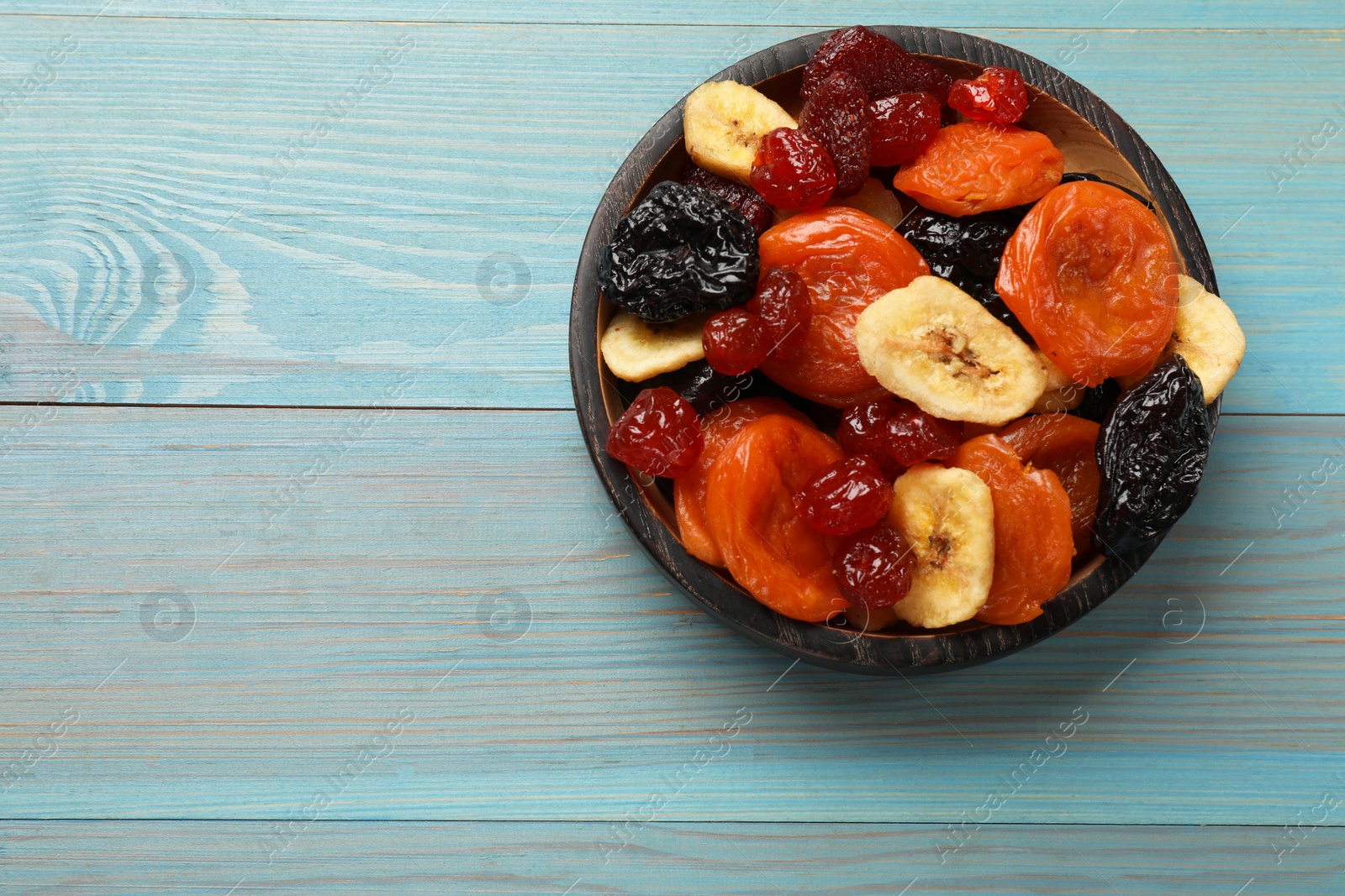 Photo of Mix of delicious dried fruits on light blue wooden table