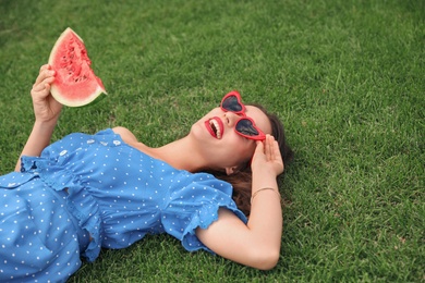 Photo of Beautiful young woman with watermelon on green grass outdoors