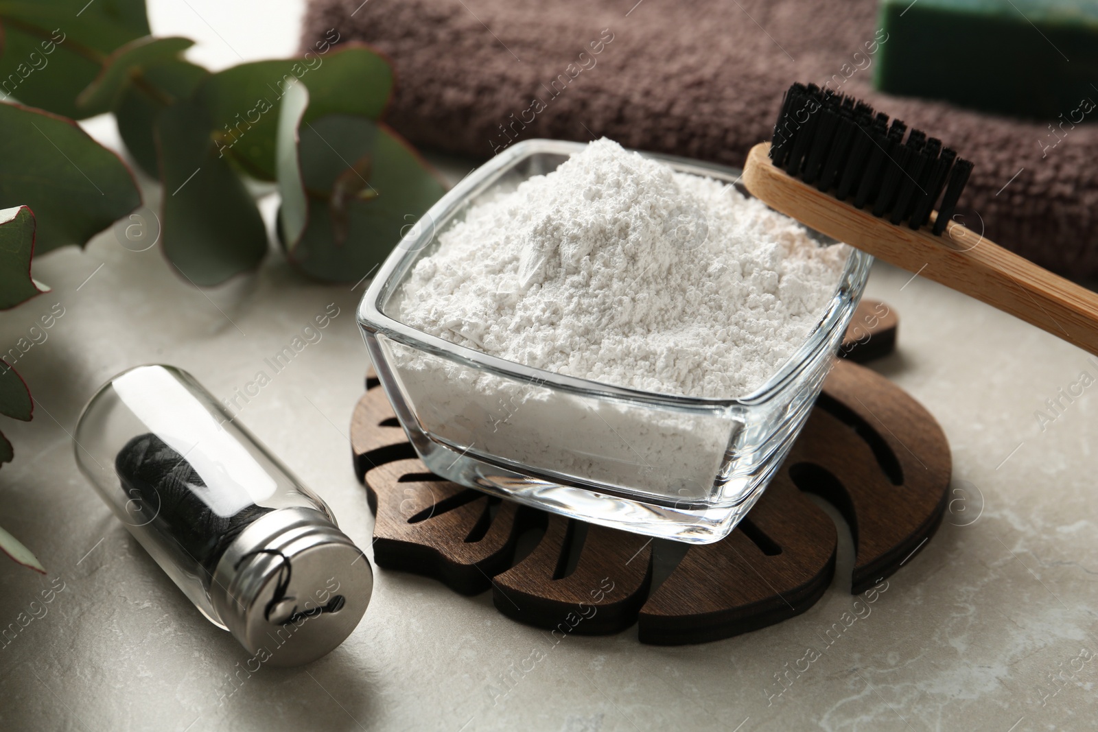 Photo of Tooth powder, brush and floss on light grey table, closeup