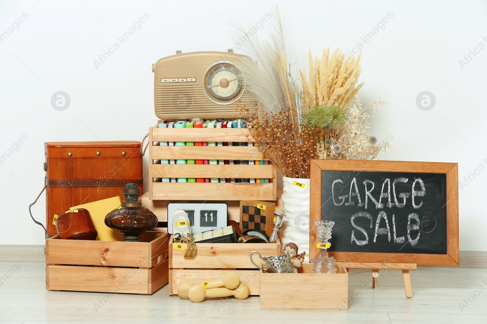 Photo of Sign Garage Sale written on blackboard and many different stuff near white wall