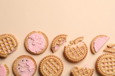 Photo of Tasty sandwich cookies with cream on beige background, flat lay. Space for text