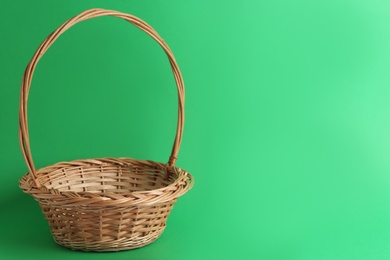 Photo of Empty wicker basket on green background, space for text