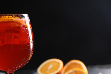 Photo of Glass of tasty Aperol spritz cocktail against black background, space for text