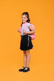 Back to school. Cute girl with backpack on orange background