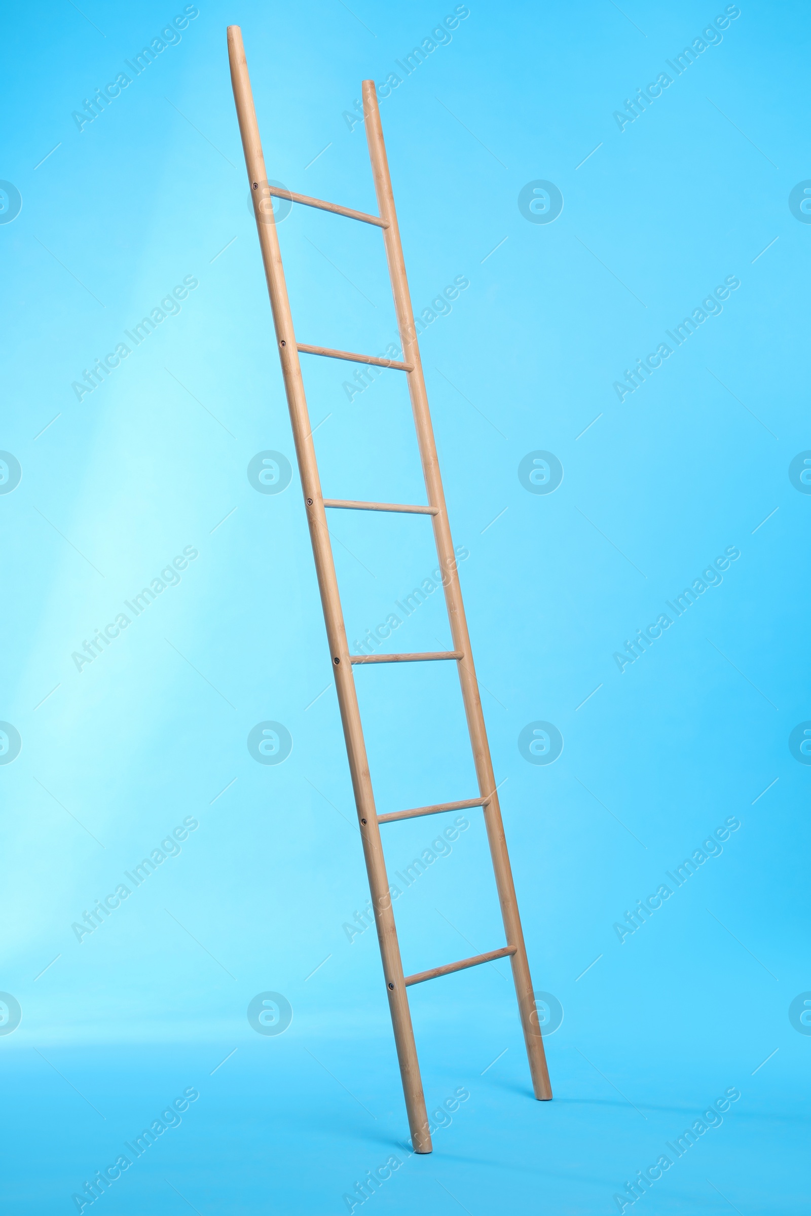 Photo of Modern wooden ladder on light blue background