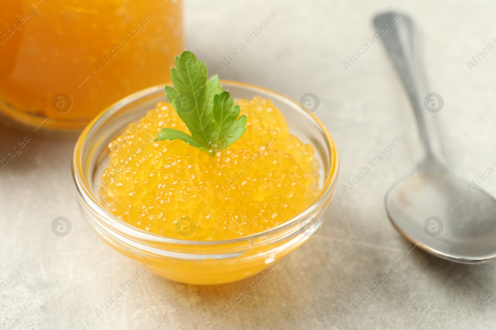 Photo of Fresh pike caviar in bowl, parsley and spoon on light grey table, closeup