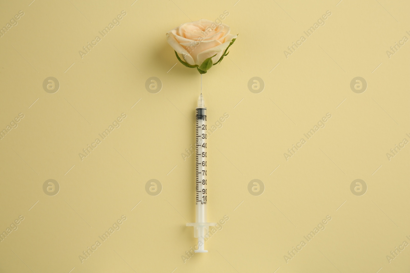 Medical syringe and beautiful rose on pale yellow background, top view Photo of Medical syringe and beautiful rose on pale yellow background, top view