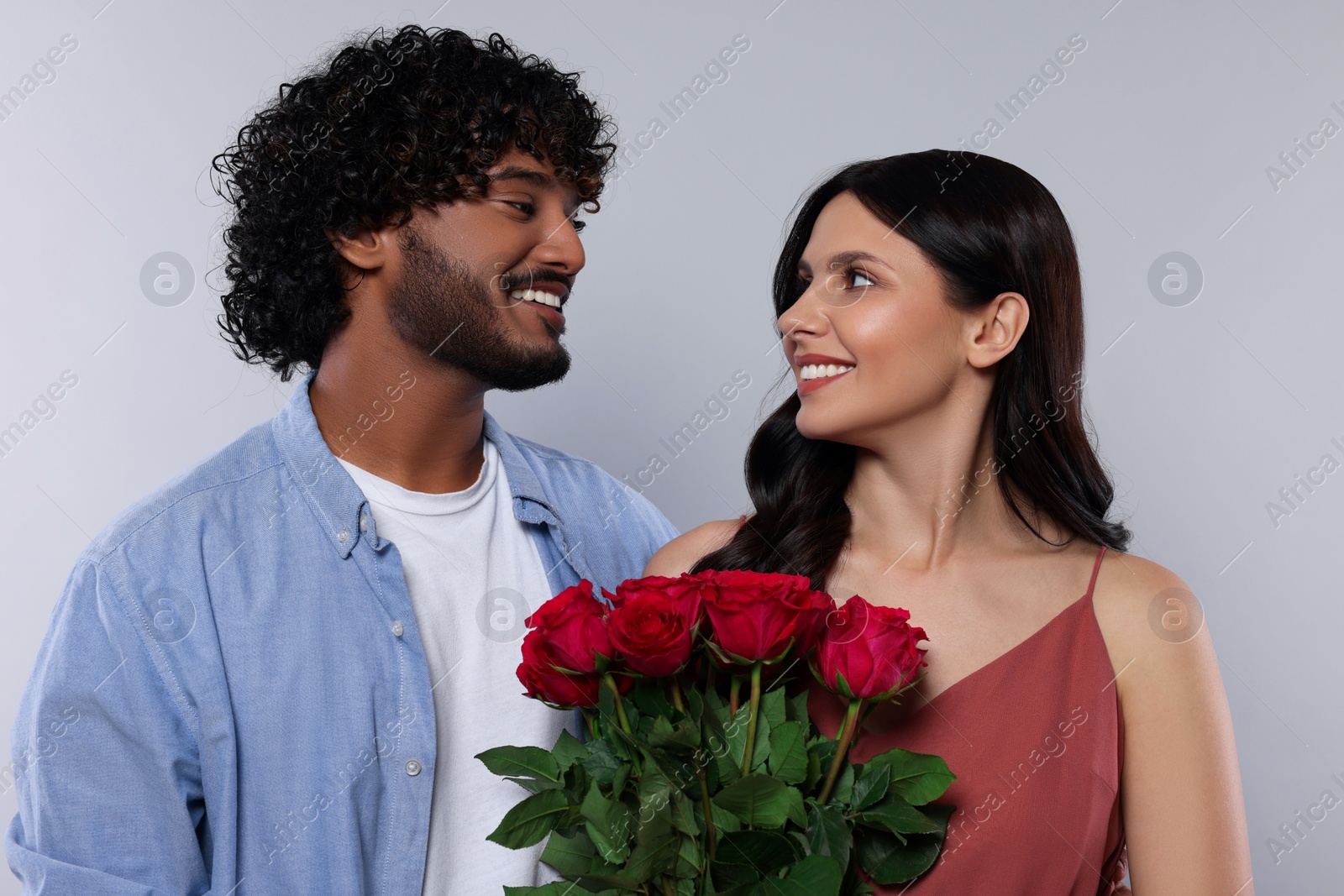 Photo of International dating. Happy couple with bouquet of roses on light grey background