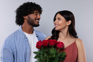 Photo of International dating. Happy couple with bouquet of roses on light grey background