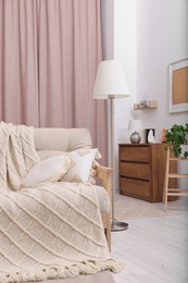 Photo of Comfortable sofa, cushions and blanket in cozy room. Interior design