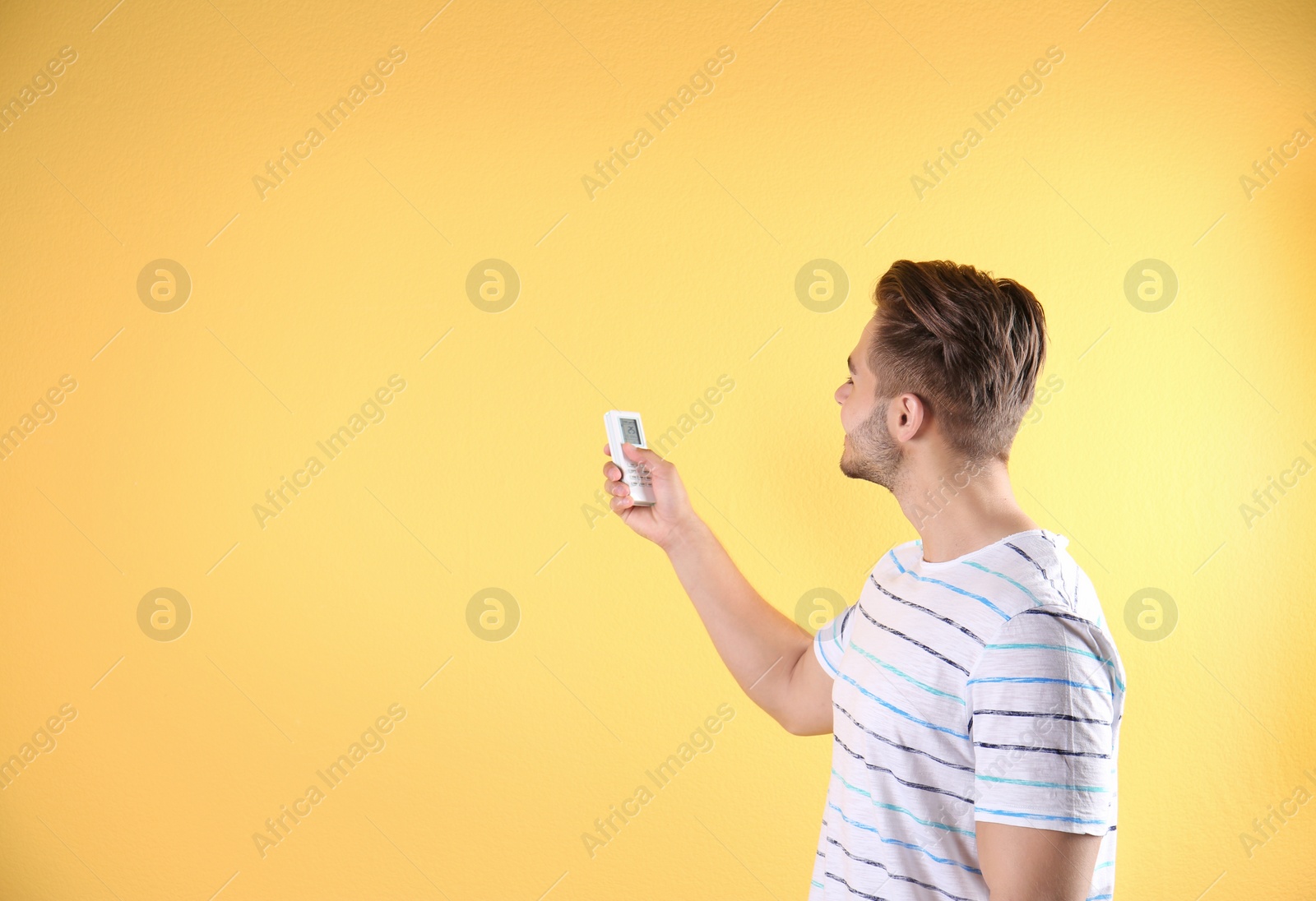 Photo of Young man with air conditioner remote on color background