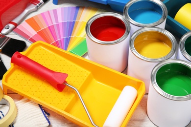 Photo of Cans of paint and decorator tools on wooden floor