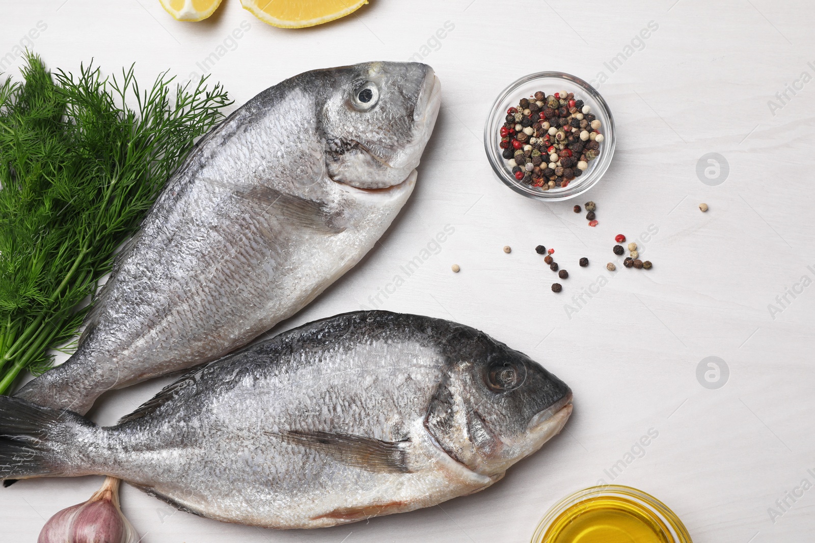 Photo of Raw dorado fish, dill and peppercorns on white wooden table, flat lay