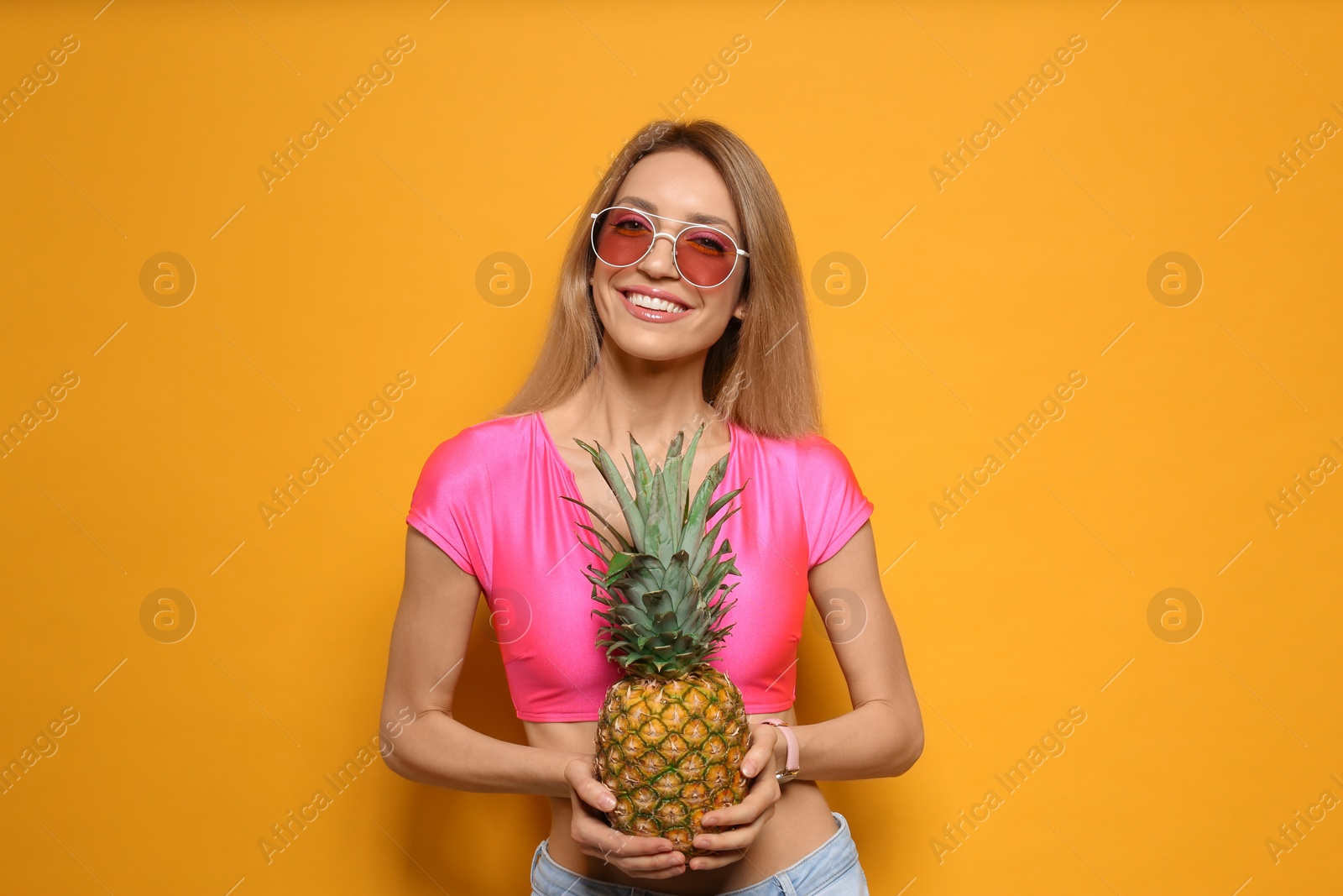 Photo of Young woman with fresh pineapple on yellow background. Exotic fruit