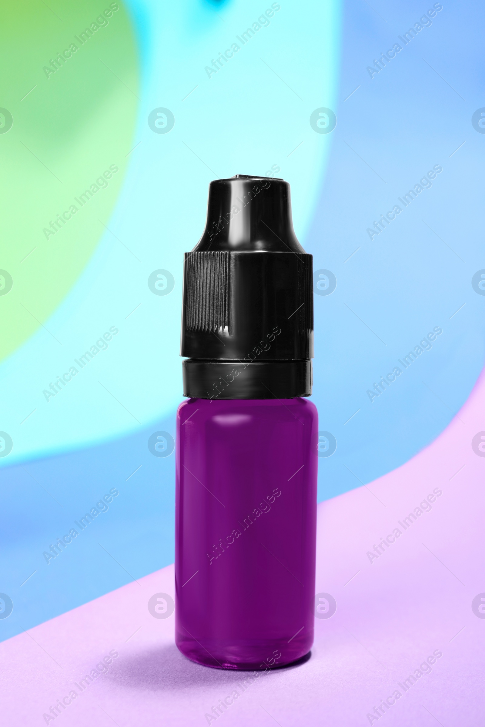 Photo of Bottle with purple food coloring on bright background