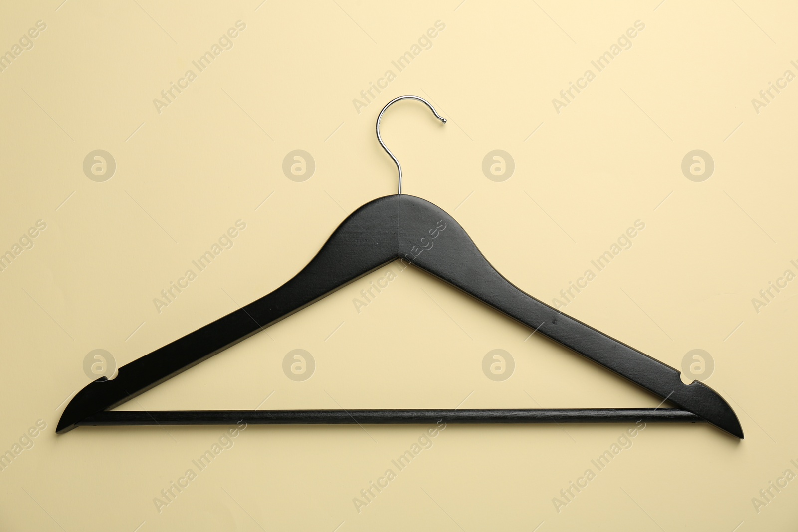 Photo of Black hanger on pale yellow background, top view
