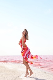 Photo of Beautiful woman in swimsuit posing near pink lake on sunny day