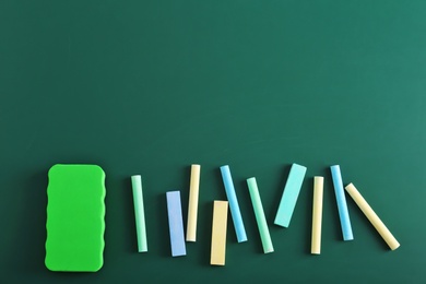 Pieces of chalk and blackboard duster on green background, top view