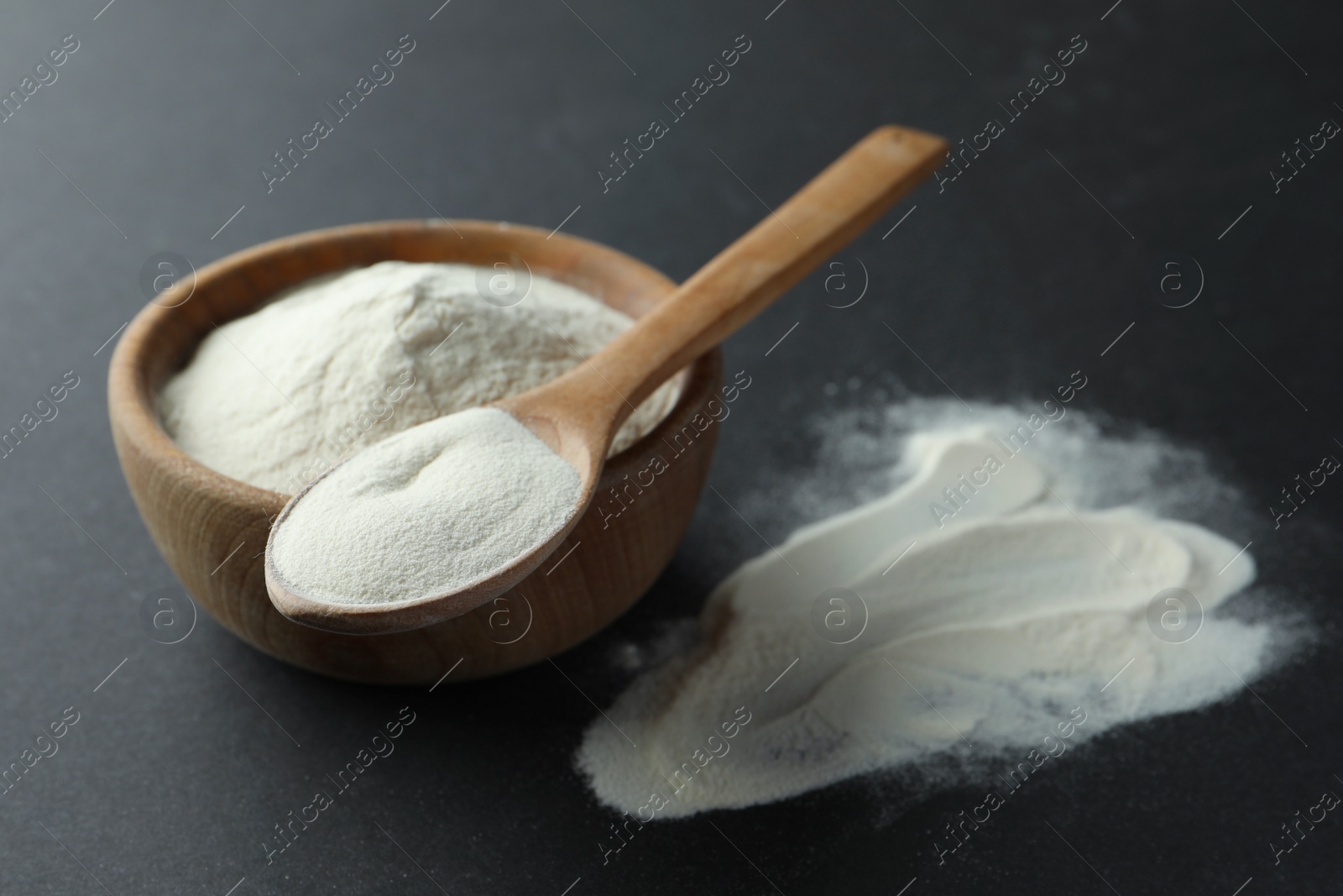 Photo of Spoon and bowl of agar-agar powder on black background, closeup