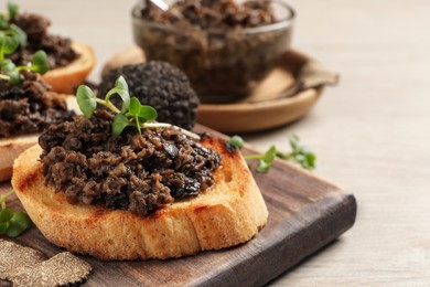 Photo of Delicious bruschetta with truffle sauce and microgreens on white wooden table, closeup. Space for text