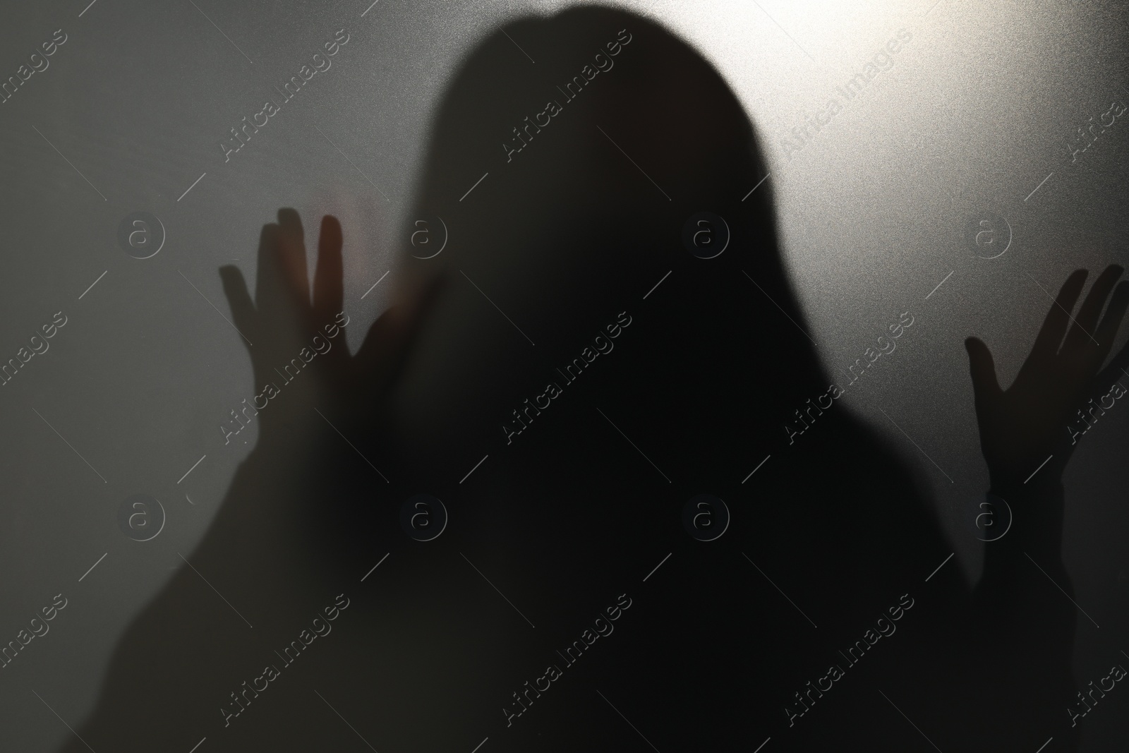 Photo of Silhouette of ghost behind glass against grey background