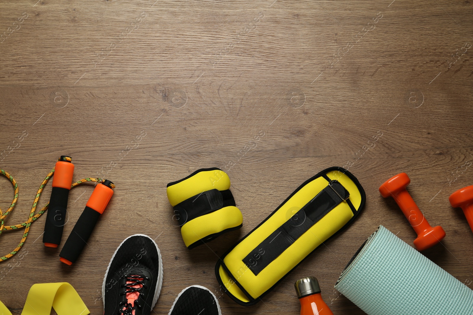 Photo of Yellow weighting agents and sport equipment on wooden table, flat lay. Space for text