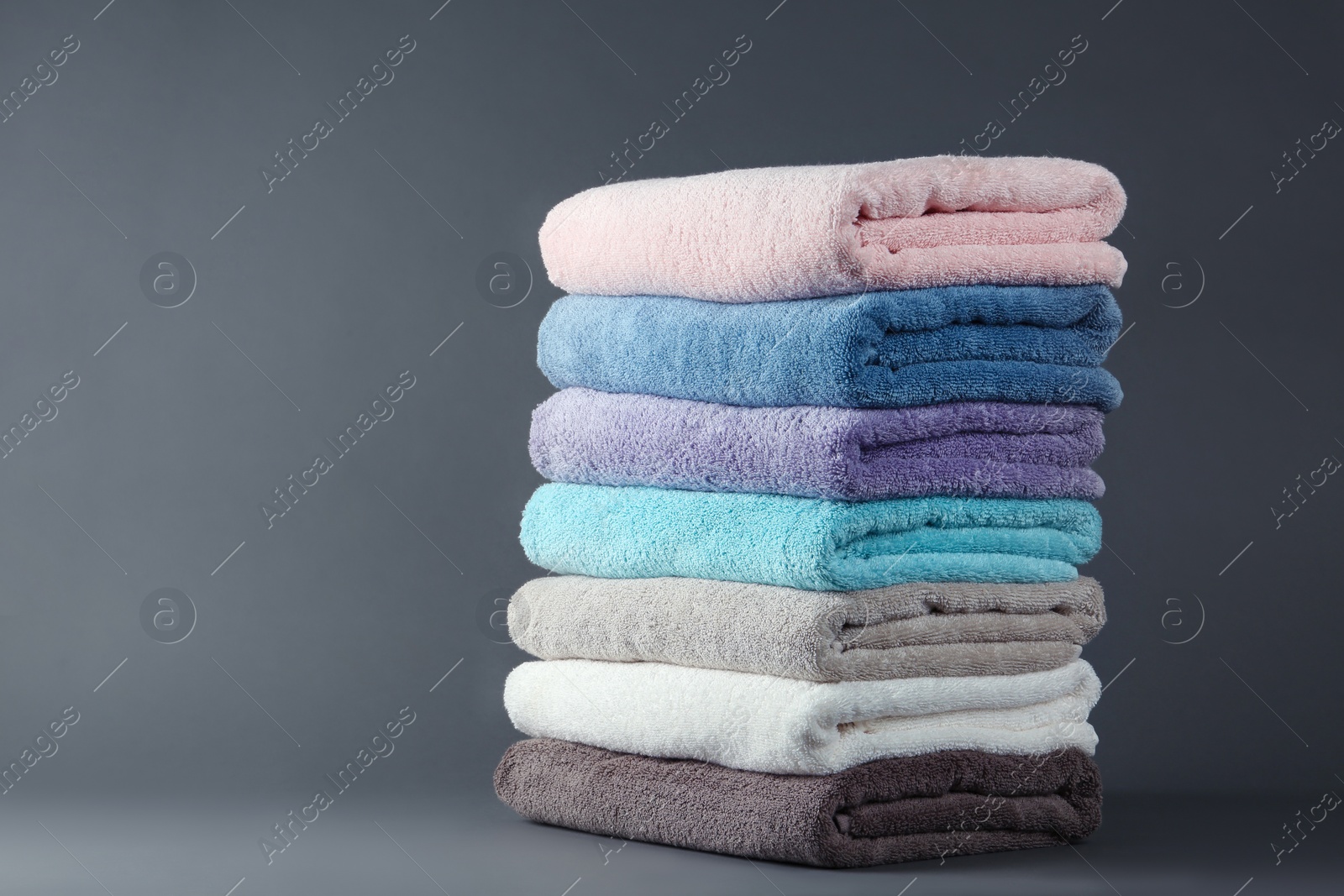 Photo of Different fresh soft terry towels on grey background