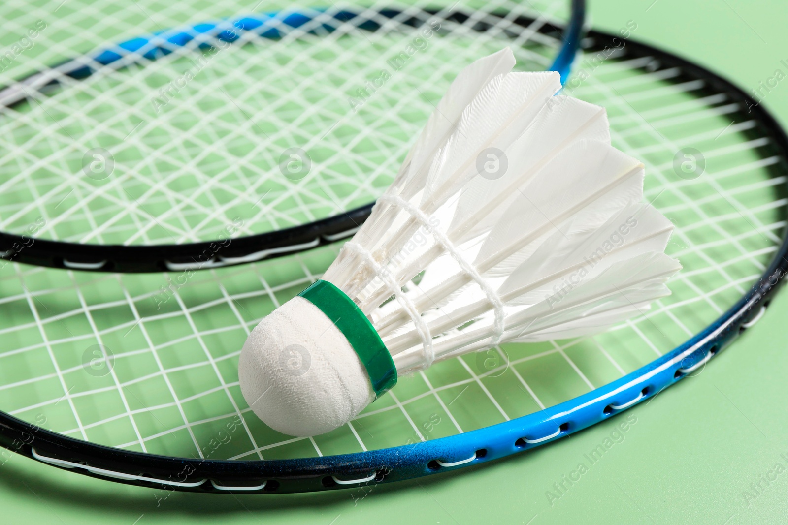 Photo of Feather badminton shuttlecock and rackets on green background, closeup