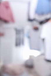 Blurred view of modern dressing room with different stylish clothes and accessories