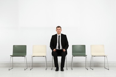 Man with clipboard waiting for job interview in office hall