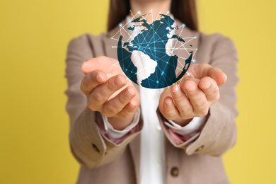 Global network technology. Woman demonstrating planet with connection lines on yellow background, closeup