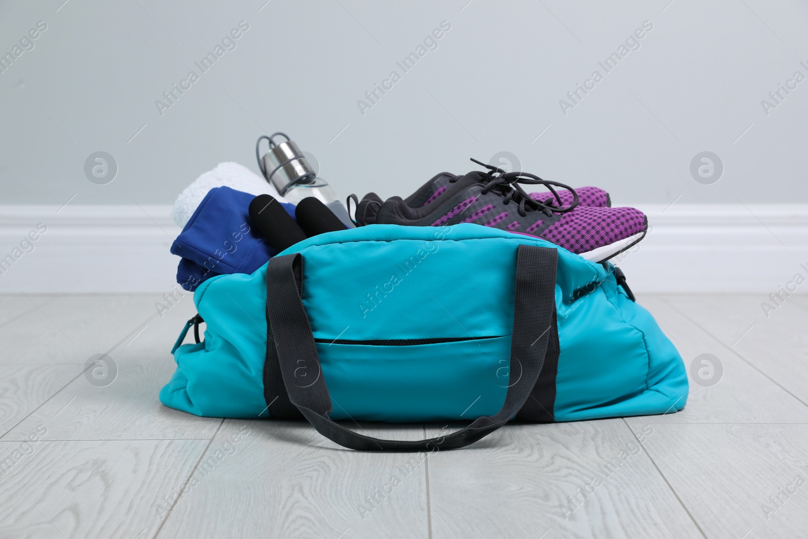 Photo of Bag with different sports equipment on wooden floor indoors