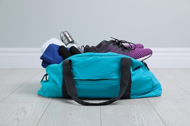 Photo of Bag with different sports equipment on wooden floor indoors